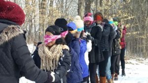 One student leading a line of blindfolded students in winter experiential education activity.